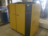 a yellow air compressor sitting in a warehouse next to a blue barrel