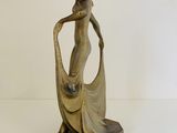bronze statue of a woman holding a bag on a wooden base