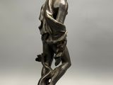 a bronze statue of a man holding a fish on a rock
