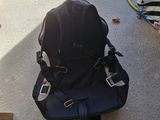 a black backpack sitting on the ground next to a pile of luggage