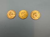 three gold coins, one of which has a picture of a man and a woman on it