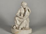 statue d'une femme assise sur un rocher, tenant un oiseau dans la main