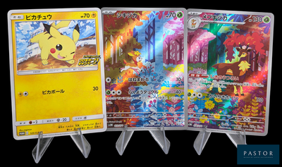 Trois cartes Pokémon sont exposées sur un présentoir devant un fond noir.