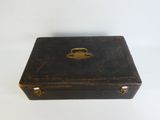 une vieille valise noire avec une poignée dorée sur un fond blanc