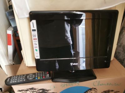 un téléviseur posé sur un carton, avec une télécommande