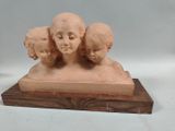 a sculpture of three heads on a wooden base