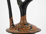 a black and orange vase with a handle on top of it