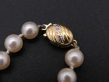 a pearl bracelet with a gold bead clasp on it