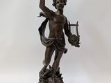 an antique bronze statue of a man holding a harp on a wooden base
