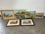 three framed paintings of boats and buildings on display in a room