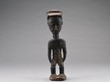 une vieille figurine en bois représentant un homme avec un chapeau sur la tête