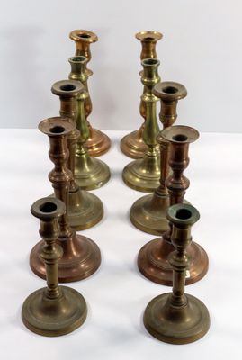 quatre bougeoirs en laiton posés sur une table blanche, sur fond blanc