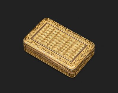 une petite boîte en or avec un motif sur le couvercle
