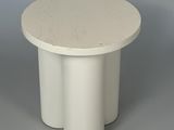 une image représentant une table blanche au plateau rond posée sur une surface grise