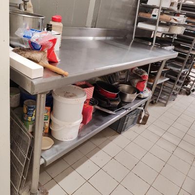 une cuisine avec un plan de travail en inox sur lequel sont posés de nombreux plats et casseroles