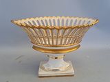 a white and gold bowl on a stand on a table