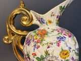a white vase with a gold handle on a table