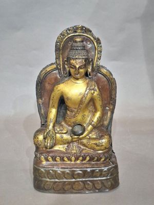 statue of a buddha sitting on a chair with a ball in his hand