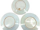 three white plates with gold rims on a white background