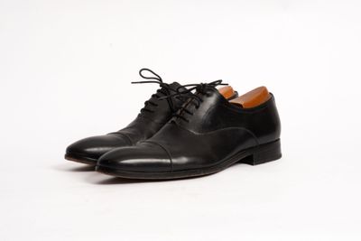 a close up of a pair of black shoes on a white surface