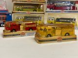 three toy fire trucks sitting on a table in front of a shelf of other toys