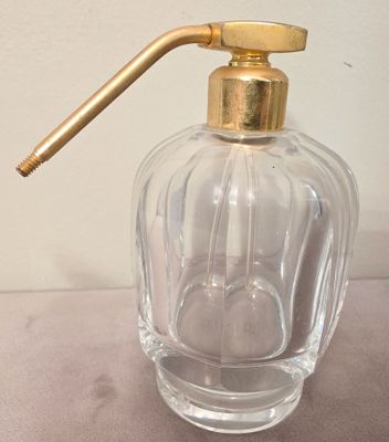 a clear glass bottle with a gold handle on a table