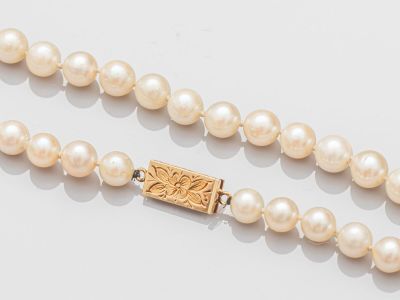 un gros plan sur un collier de perles muni d'un fermoir en or
