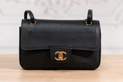 a black chanel bag sitting on top of a wooden table
