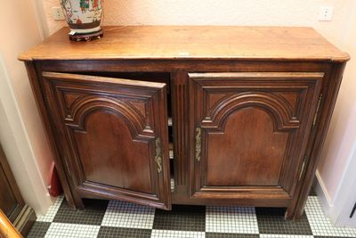 une armoire en bois à deux portes, sur laquelle est posé un vase