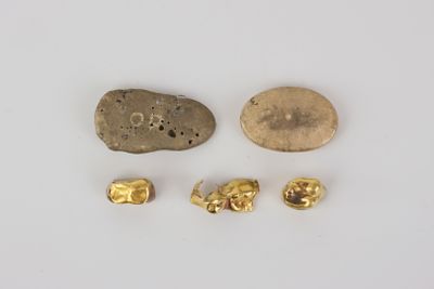 three gold nuggies and a rock on a white surface