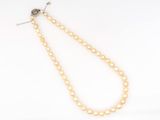 a close up of a pearl necklace on a white surface