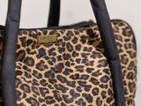 a close up of a leopard print handbag with a black handle