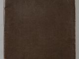 un vieux livre à la couverture marron posé sur une table blanche