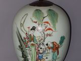 un vase blanc avec un tableau posé sur une table