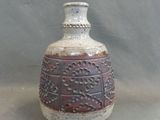 a brown and white vase sitting on a gray surface