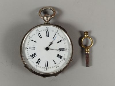 une horloge en argent avec des chiffres romains et une clé