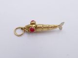 a close up of a gold fish charm on a white surface