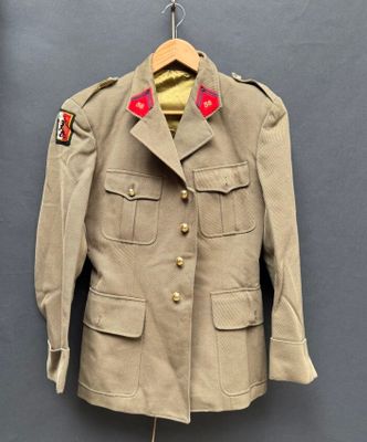 une vieille veste militaire suspendue à un cintre accroché au mur
