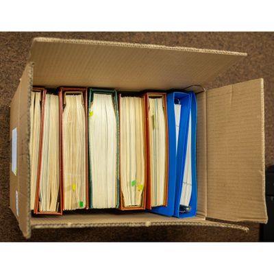a box full of files sitting on the floor next to a remote