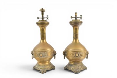 pair of antique brass oil lamps on pedestals on a white background