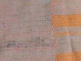 an orange and grey striped rug with a small patch on top of it