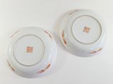 two white plates with orange designs on them on a white surface