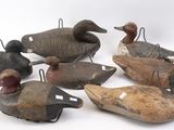 Plusieurs canards en bois sont alignés en rang sur une surface blanche