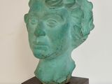 statue représentant la tête d'une femme, posée sur un socle en bois