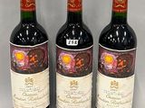 three bottles of red wine sitting next to each other on a table