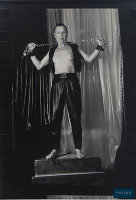 black and white photograph of a man in leather pants holding a pair of scissors