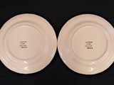 two white plates with black writing on them sitting on a black surface