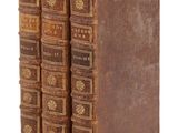 trois vieux livres posés l'un sur l'autre sur une surface blanche