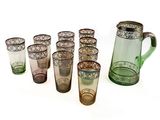 de nombreux verres de différentes couleurs et un pichet sur la table