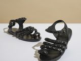 une paire de sandales noires posées sur une surface blanche